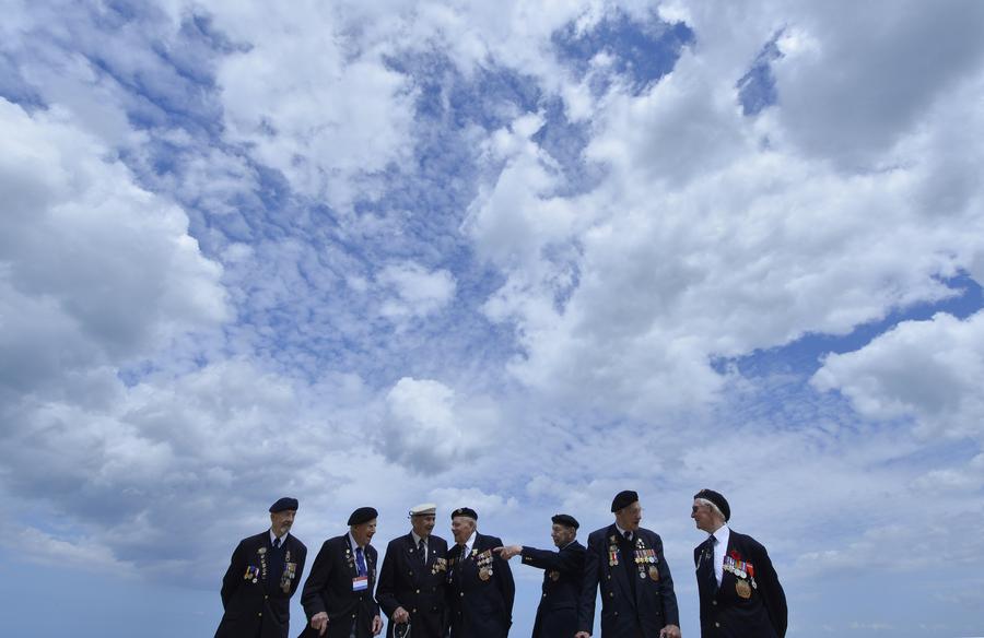 Les vétérans britanniques originaires de Wiltshire (de gauche à droite), Wally Ball, Doug Blakey, Bernie Howell, Bob Corney, George French, Gordon Smith et Albert William se tiennent sur la Sword Beach (l’une des cinq plages du débarquement allié) à Hermanville-sur-Mer sur la c?te normande, le 5 juin 2014. [Photo/agences]