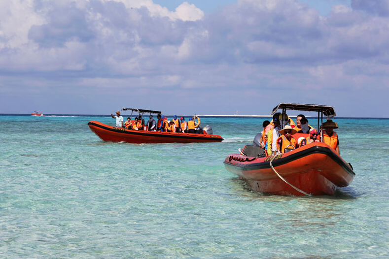 Des touristes prennent des bateaux rapides pour aller aux ?les Xisha. [Photo/Xinhua]