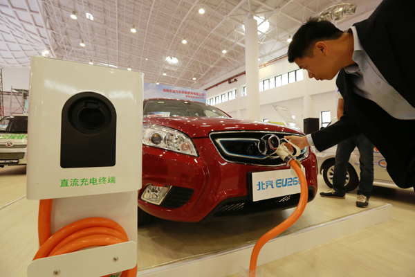 à Hainan, où le secteur des véhicules à énergie nouvelle conna?t un fort engouement, un visiteur s'essaye à la recharge d'un véhicule électrique. [Crédit photo : China Daily]