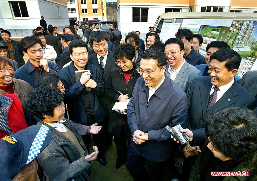 Photo d'archive prise le 3 novembre 2005 montrant Li Keqiang parlant avec des gens qui ont emménagé dans de nouveaux logements grace à la réhabilitation des bidonvilles à Fushun, dans la province du Liaoning (nord-est), en Chine.