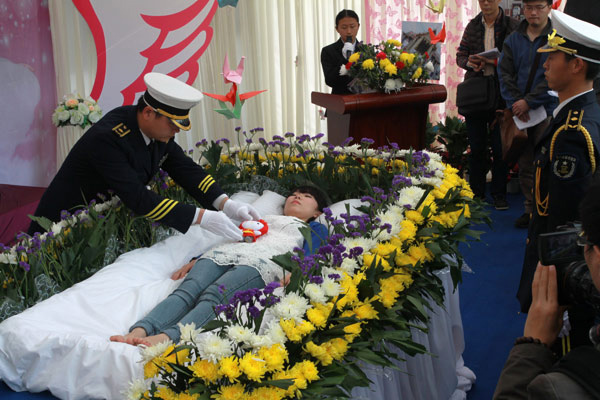 Un employé des pompes funèbres ajuste les vêtements de Zeng Jia, une étudiante ayant organisé ses propres fausses funérailles à Wuhan, en Chine centrale dans la province du Hubei, le 30 mars 2013.