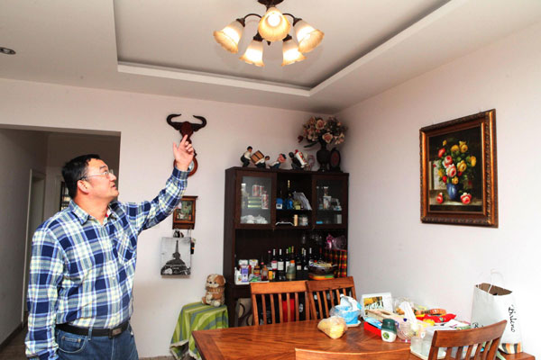 Dong Qiang montre une lampe qui utilise l'électricité produite à partir de l'un de ses panneaux solaires à Tianjin, le 6 avril 2013.