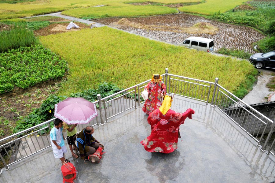 Le 18 ao?t 2013, dans le district autonome Maonan de Huanjiang dans la province du Guangxi, Tan Shengci joue du tambour quand ses deux amis présentent un spectacle de la danse Nuo pour deux gar?ons, qui suivent chez de lui une formation de la fabrication des masques de la danse Nuo. (Photo : Xinhua)