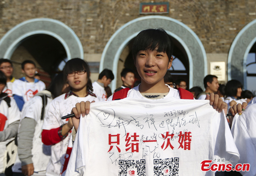 Un étudiant montre un T-shirt imprimé avec la phrase ? Ne nous marions qu'une fois ? à Nanjing, capitale de la Province du Jiangsu, dans l'Est de la Chine, le 17 novembre 2013. Plus de 100 résidents locaux et bénévoles ont pris part à une campagne lan?ant un appel pour des conceptions positives et saines du mariage dimanche à Nanjing. [Photo/China News Service]