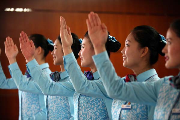 Des agents de bord ferroviaires montrent leurs gestes de service standard lors d'un séminaire à Qingdao, dans la Province du Shandong, mercredi. L'événement visait à améliorer la qualité du service fourni par les agents au cours de la saison hivernale. [Photo Xu Chongde / pour le China Daily]