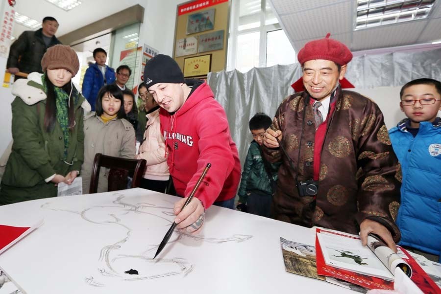 Jonathan, un Américain, a rencontré des artistes folkloristes et des enfants de la communauté de Haocheng pour exécuter une peinture sur le thème du cheval et certains travaux de calligraphie pour accueillir le prochain Nouvel An lunaire -l'Année du Cheval- à Nantong, dans la Province du Jiangsu, le 24 janvier. [Photo Xu Peiqin / Asianewsphoto]