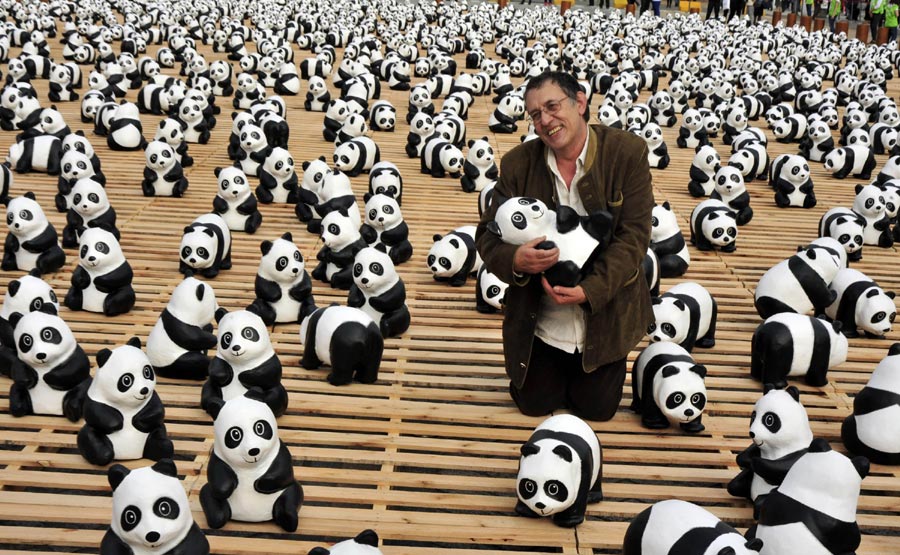 L'artiste fran?ais Paul Grangenon pose pour se faire photographier avec ses ?uvres, des pandas en papier, lors de l'exposition en plein air intitulée ? Pandas World Tour - Taipei ? sur la Place des Citoyens à Taipei, au sud-est de Taiwan, en Chine, le 27 février 2014. Un total de 1 600 pandas et ours à collier de Taiwan fabriqués en papier respectueux de l'environnement ont été exposés ici jeudi. L'événement vise à promouvoir la protection de l'environnement et la sensibilisation du public à la conservation des animaux. Tous les pandas et ours à collier en papier exposés seront proposés pour une vente de charité après la conclusion de l'événement le 30 mars. [Photo/Xinhua]